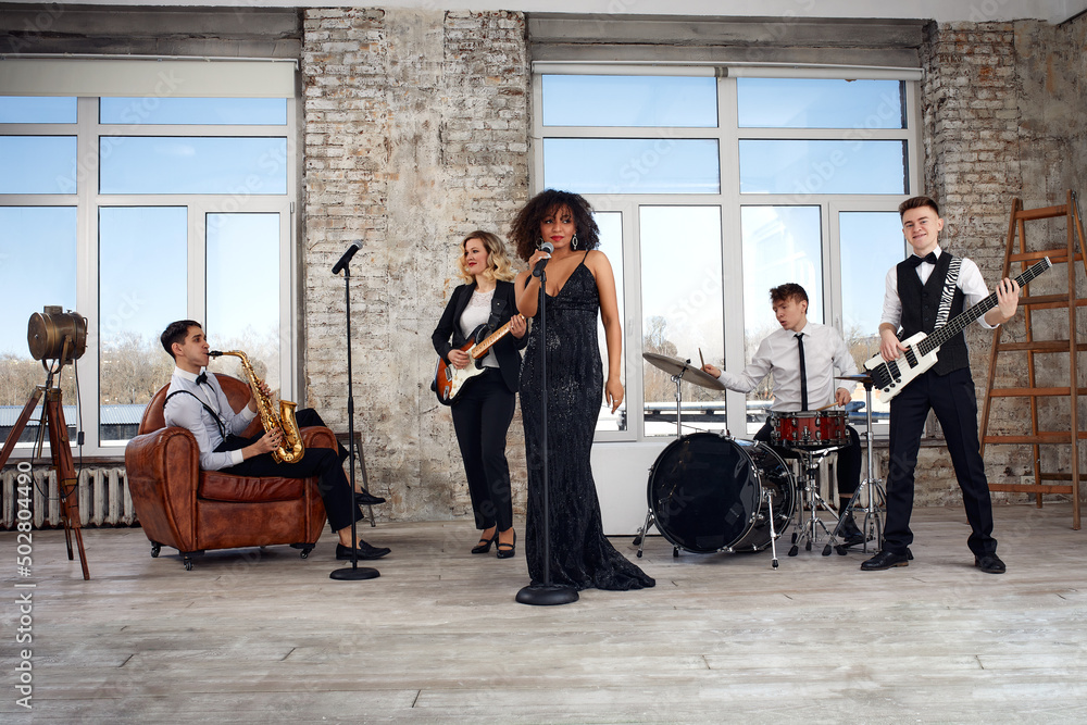 Repetition of multi ethnic jazz band in loft. Bass guitar player