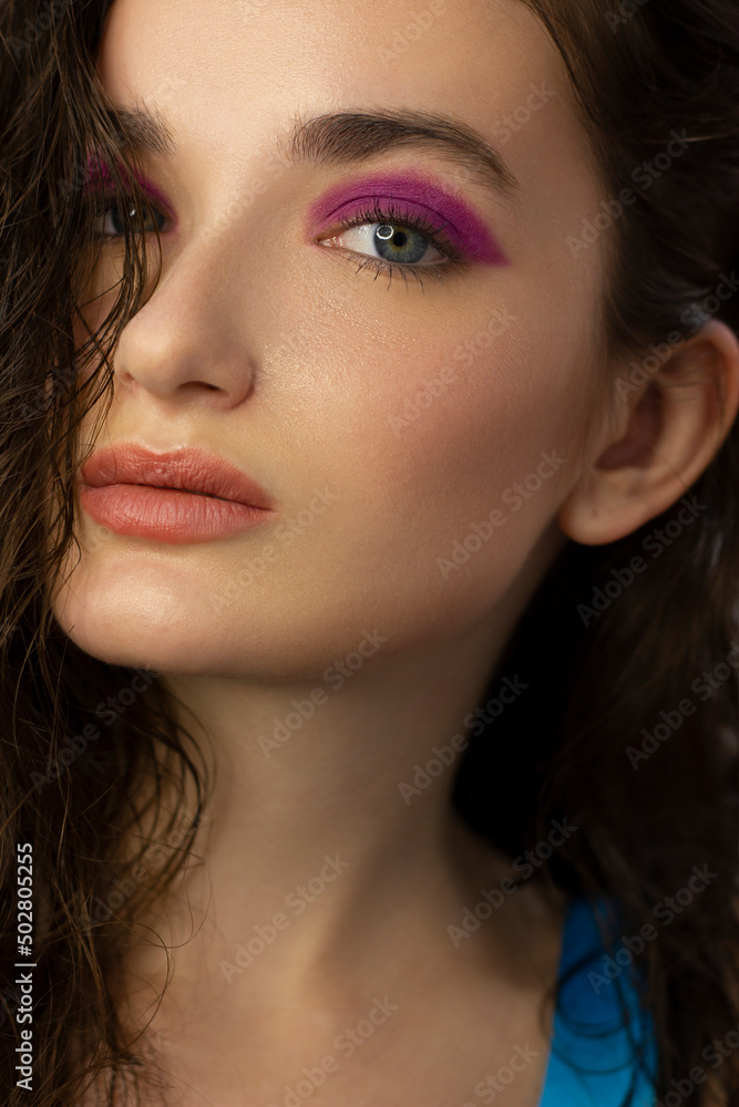 Obraz premium Beautiful brunet model woman face with grey eyes and perfect make-up make smile on camera. Portrait of beauty with nude lips and eyes liner, thick eyesbrow . Female face with clear skin close-up.