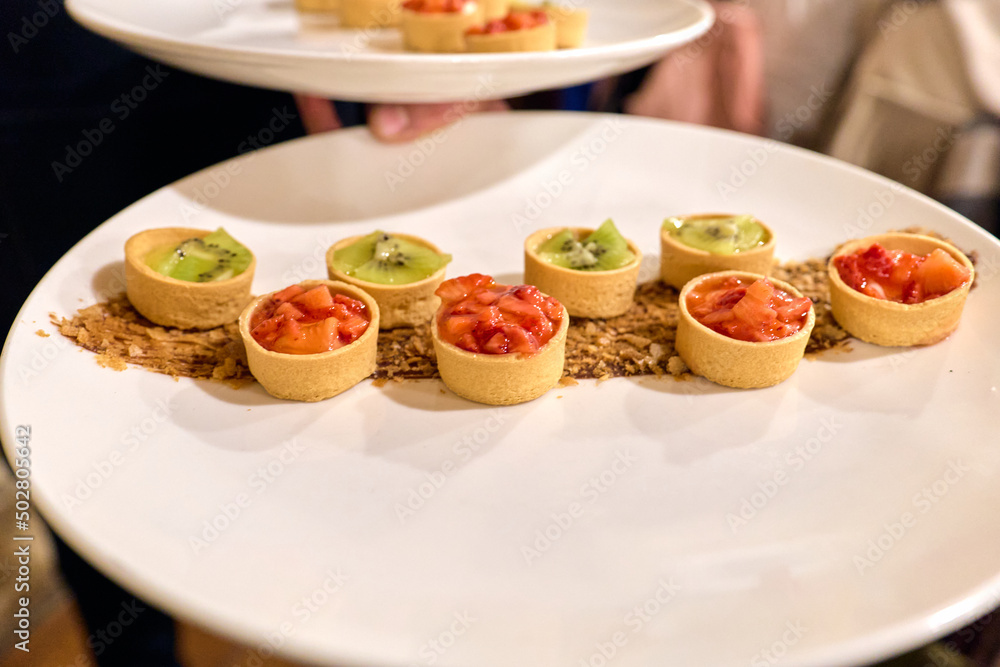 White round plate with fruit tartlets or small pies White round plate with fruit tartlets or small pies