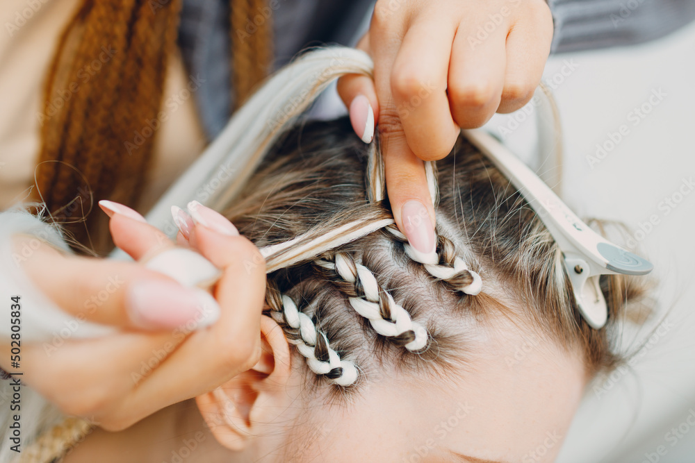 Hairstylist braided afro braids dreadlocks kanekalon pigtails hair of female client in barber salon. - obrazy, fototapety, plakaty 
