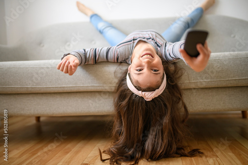 Girl Changing Channel With Remote Control In Front Of Television At Home upside down