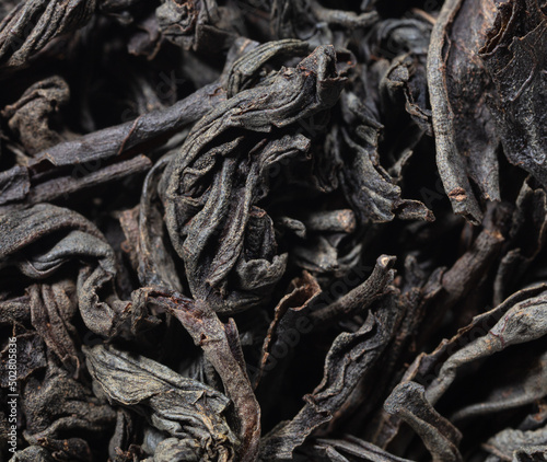 Dried black tea leaves as background.