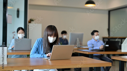 Young Asian employee with face masks in the office after lockdown, New normal and return to work concept