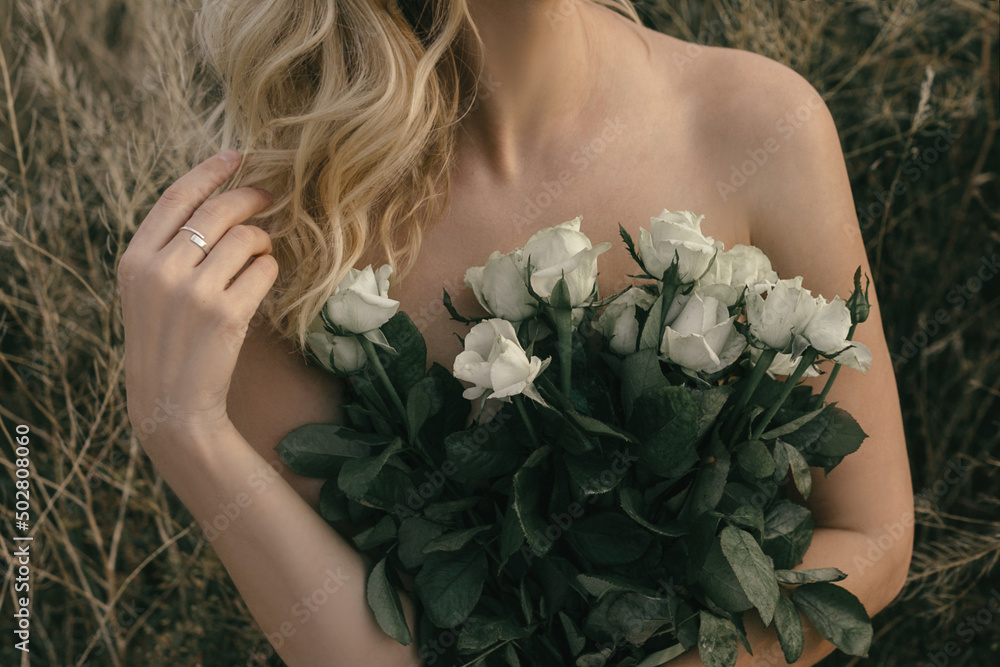 Bouquet of roses on a romantic date in a rustic field, nude girl close-up with a bouquet of white flowers