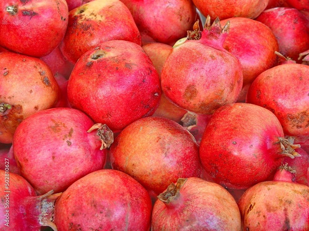 background of many red ripe pomegranates for sale at greengrocer background of many red ripe pomegranates for sale at greengrocer