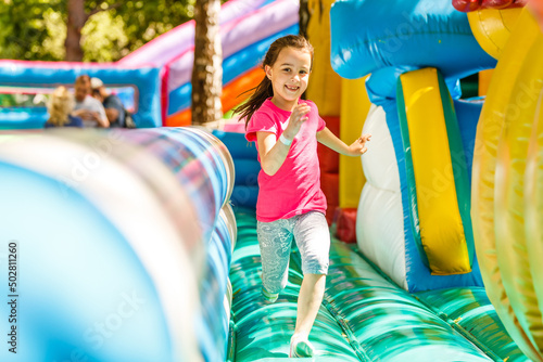 Happy little girl having lots of fun on a jumping castle during sliding.