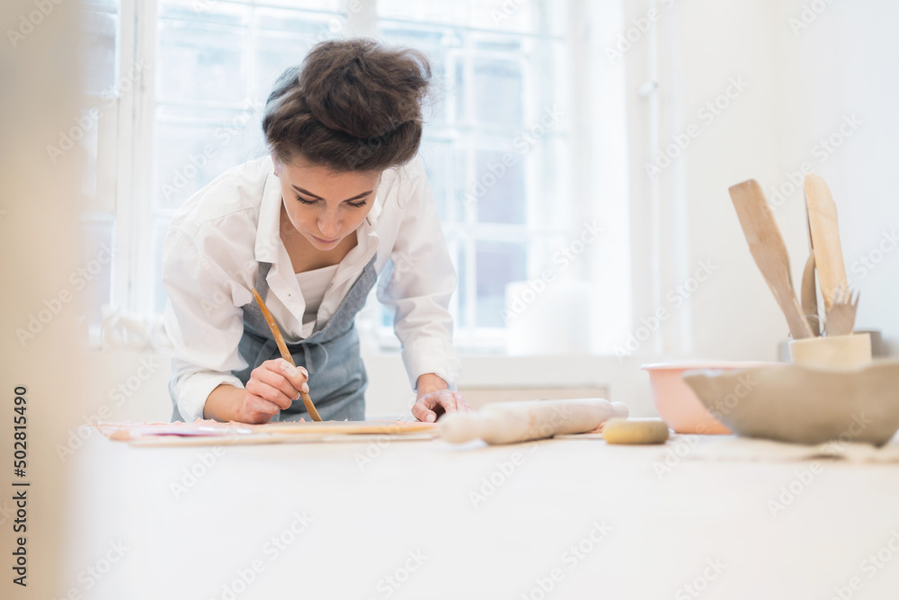 Small business woman craftsman in an apron ceramics handmade in the workshop making dishes Small business woman craftsman in an apron ceramics handmade in the workshop making dishes