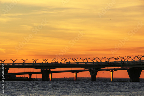 Fototapeta Naklejka Na Ścianę i Meble -  colorful sunset against the backdrop of a high-speed road passing over the sea