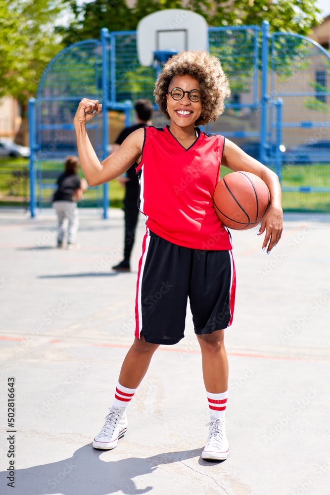 girl with afro hairstyle with a ball on a basketball court