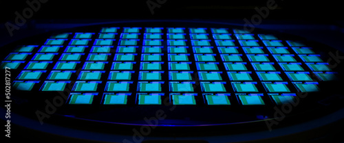Silicon wafer with chips in UV lighting. Neon. Ultraviolet Lithography. photo