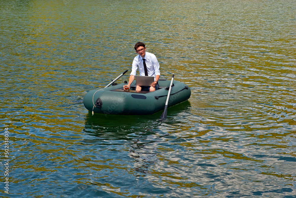 A man in a white shirt on an inflatable boat. Businessman with laptop resting on the lake. The concept of remote work, leisure and freelance.