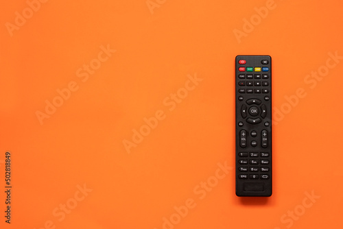 TV remote controller on orange background. Space for text. Top view photo