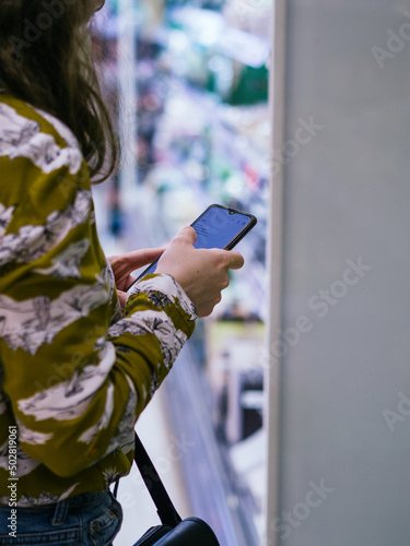 Unrecognizable caucasian woman looking at the smartpone shopping list photo