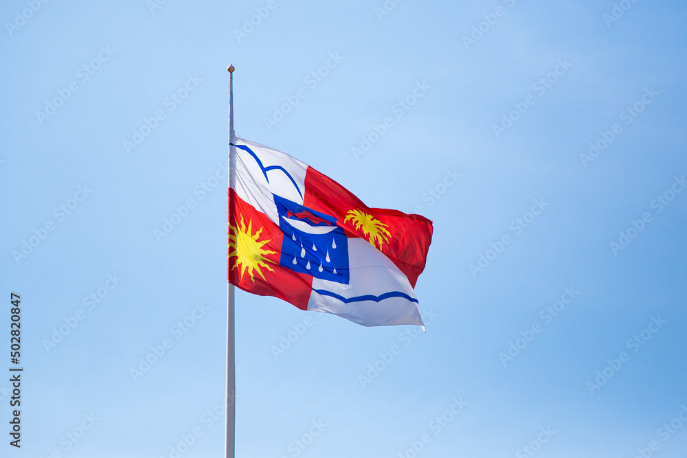 Coat of arms of Sochi against the blue sky. Russia, Krasnodar Territory, Sochi. Flag with the coat of arms of Sochi in the wind.