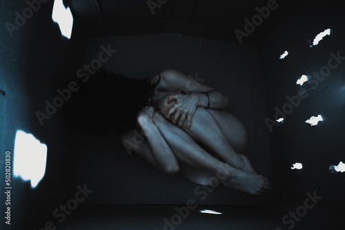 claustrophobia. Young woman with claustrophobia in a box. Fear of claustrophobia. This box is too small. Shocked young woman sitting in a cardboard box. Agoraphobia of mental illness.