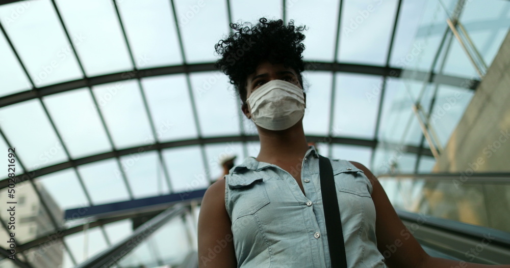 Woman commuting to work wearing pandemic face mask descending elevator Woman commuting to work wearing pandemic face mask descending elevator