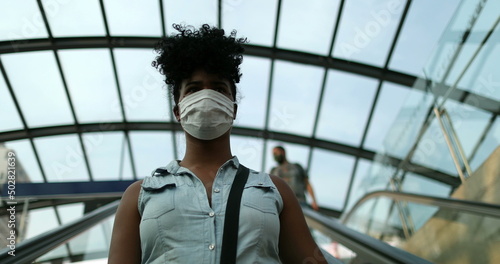 Woman commuting to work wearing pandemic face mask descending elevator