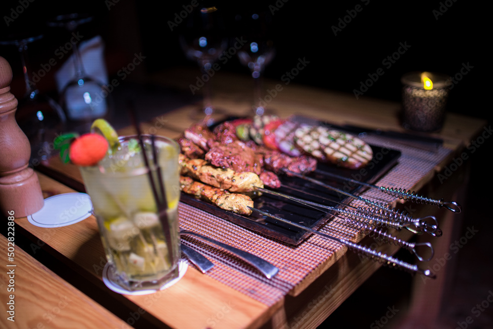 A plate of Chicken and beef BBQ with grilled tomatoes, potatoes and onions A plate of Chicken and beef BBQ with grilled tomatoes, potatoes and onions
