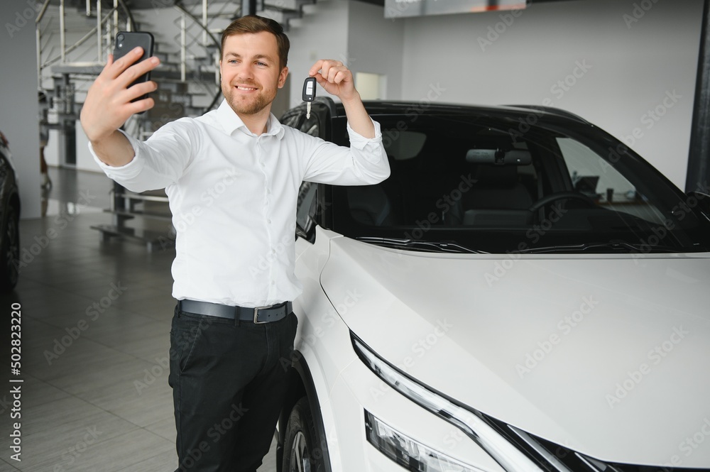 Yes, that's my new car. Customer in car dealership. Young man with keys in hand. Yes, that's my new car. Customer in car dealership. Young man with keys in hand.