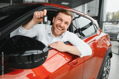 Happy man showing the key of his new car. photo