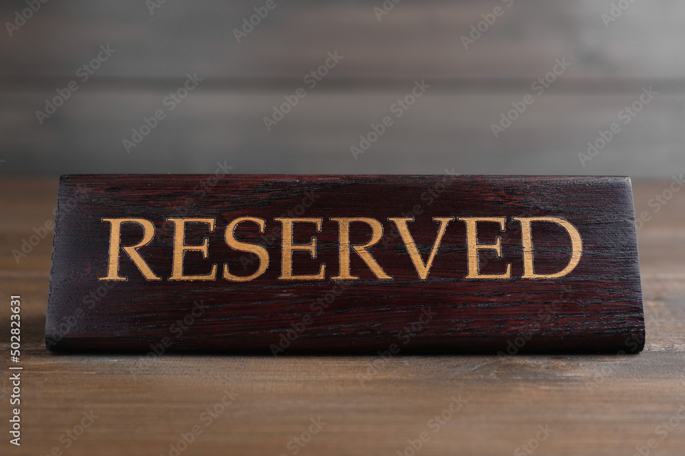 Elegant sign RESERVED on wooden surface. Table setting element Elegant sign RESERVED on wooden surface. Table setting element