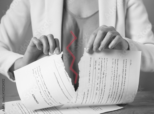 Torn document in hands. Breaking contract. Sanctions, agreement conditions and rules breaching, force majeure. Woman ripping paper agreement. Black and white. High quality photo photo