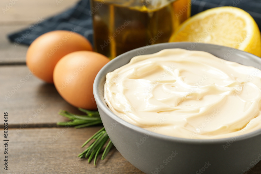 Bowl with fresh mayonnaise and ingredients on wooden table, closeup Bowl with fresh mayonnaise and ingredients on wooden table, closeup