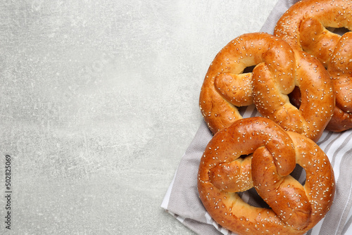 Tasty freshly baked pretzels on light grey table, flat lay. Space for text