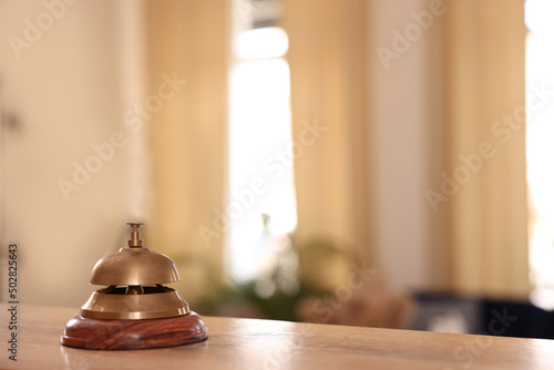 Hotel service bell on wooden reception desk. Space for text