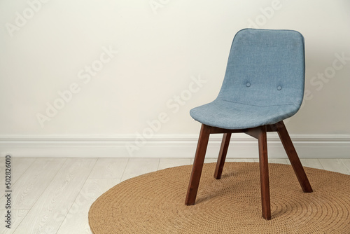 Stylish grey chair near white wall indoors. Space for text