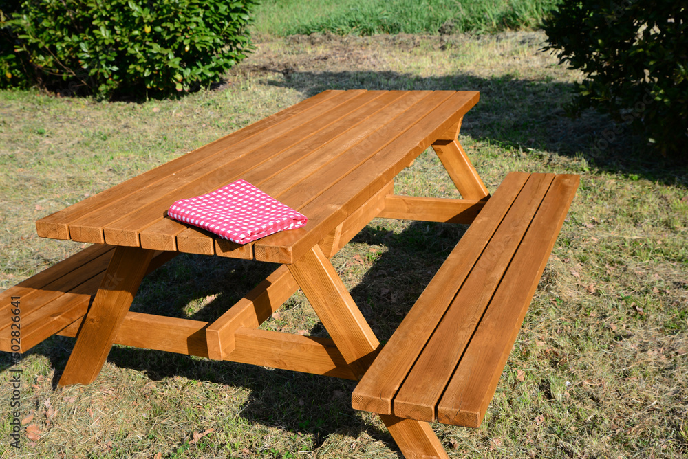 Folded red and white checkered tablecloth on wooden picnic table in park Folded red and white checkered tablecloth on wooden picnic table in park