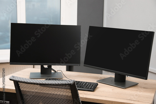 Modern interior. Workplace with multi-monitor on wooden desk in office, space for text photo