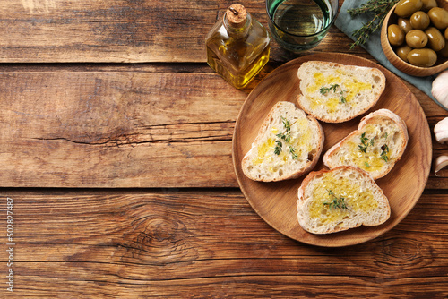 Tasty bruschettas with oil and thyme on wooden table, flat lay. Space for text