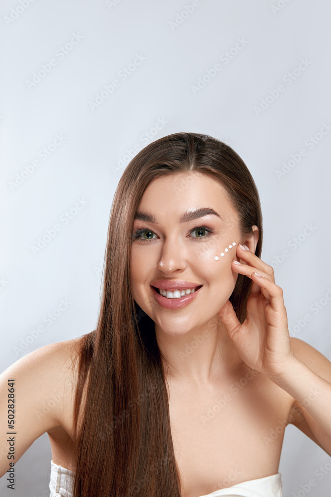 Beauty Face. Beautiful Woman With Natural Makeup Applying Cream To Her Face . Closeup Portrait Of Model Girl With Healthy Smooth Facial Skin Beauty Face. Beautiful Woman With Natural Makeup Applying Cream To Her Face . Closeup Portrait Of Model Girl With Healthy Smooth Facial Skin