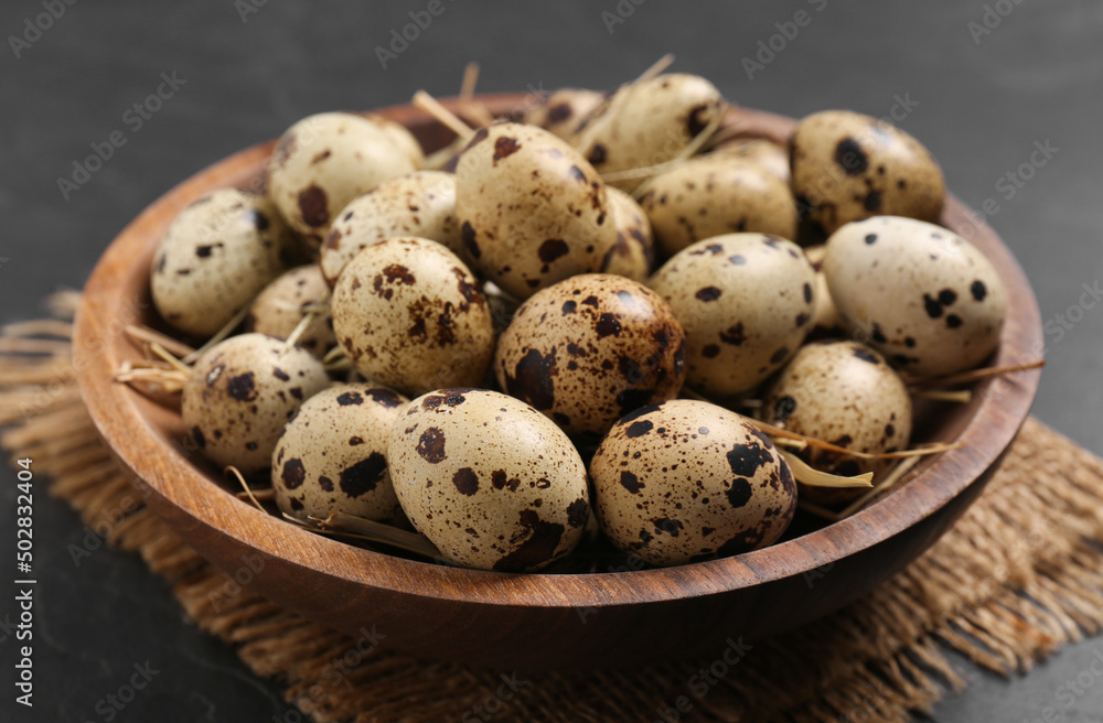 Bowl with quail eggs and straw on black table, closeup Bowl with quail eggs and straw on black table, closeup