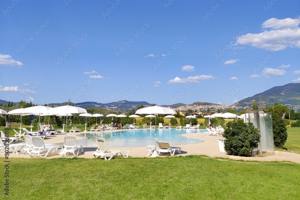 Many sun loungers by the water on a warm summer day, relaxing by the pool on the beach