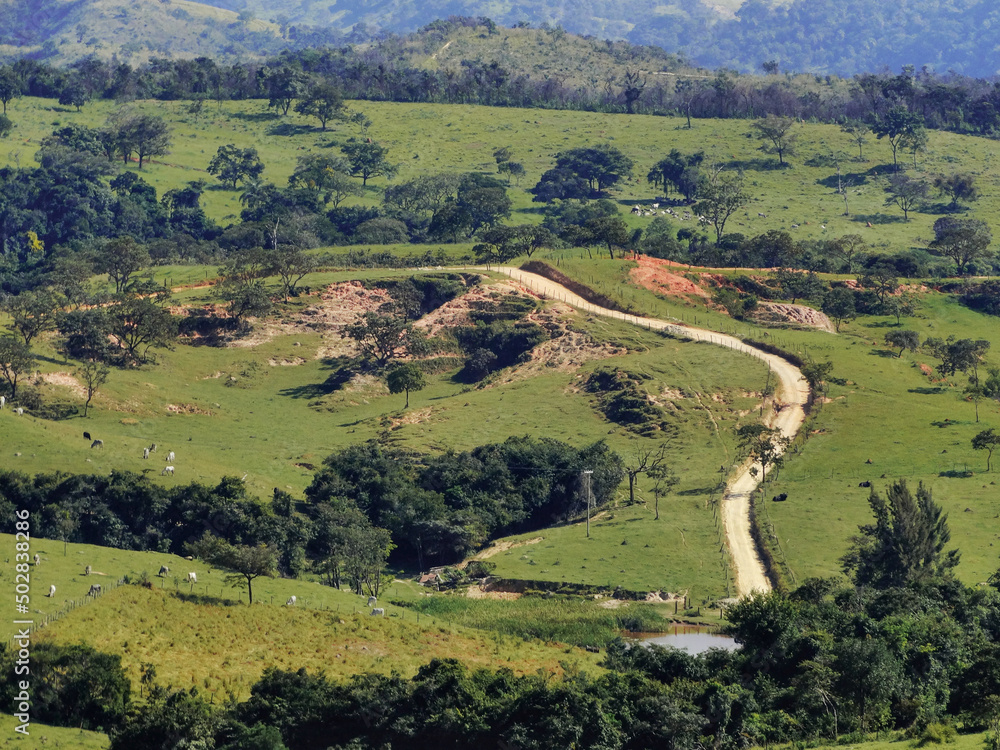 Vista de fazenda, com estrada, muita vegetação e montanhas ao redor, localizada na região rural do bairro Jardim das Oliveiras, município de Esmeraldas, Minas Gerais, Brasil.