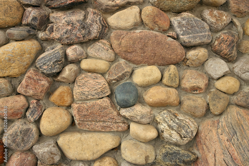 Close up of A stone Wall Built with Multi Colored Rocks and Cement Mortar. Background texture Close up of A stone Wall Built with Multi Colored Rocks and Cement Mortar. Background texture