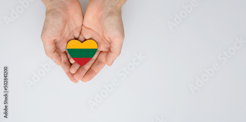 The national flag of Lithuania of arms in female hands. Flat lay, copy space.