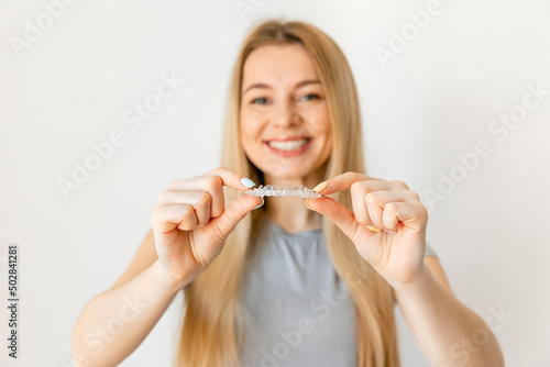 Cheerful young woman holding invisalign or invisible braces, orthodontic equipment