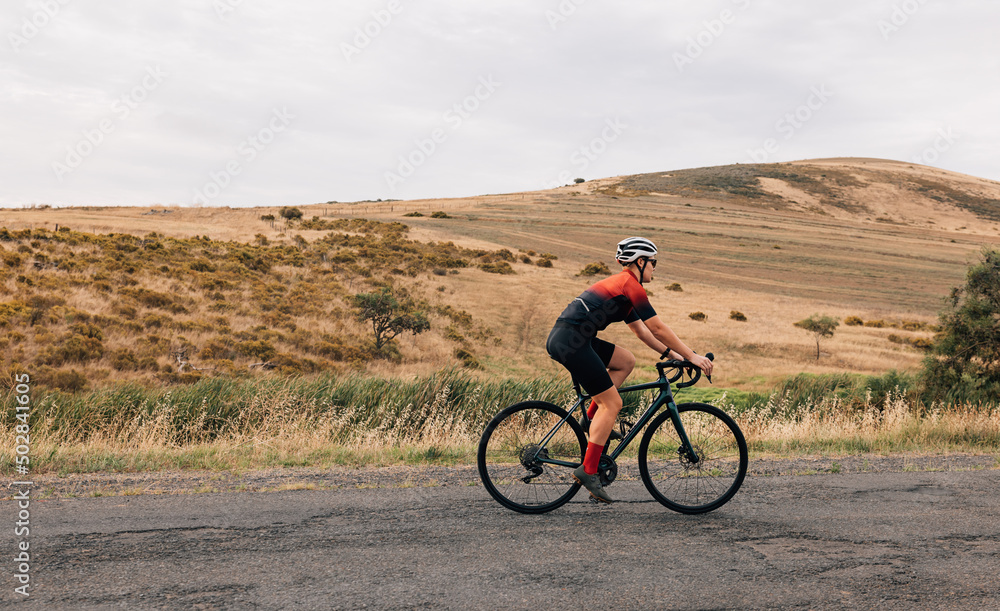 Side view of professional female cyclist in sportswear riding pro bike against beautiful landscape Side view of professional female cyclist in sportswear riding pro bike against beautiful landscape