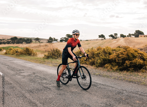 Professional woman cyclist starting to ride on empty countryside road