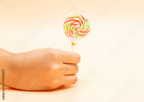 lollipop candy in a hand isolated on colorful background,