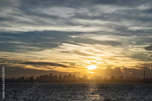舞浜から見た東京湾岸のビルの合間に落ちる夕陽 © maruboland