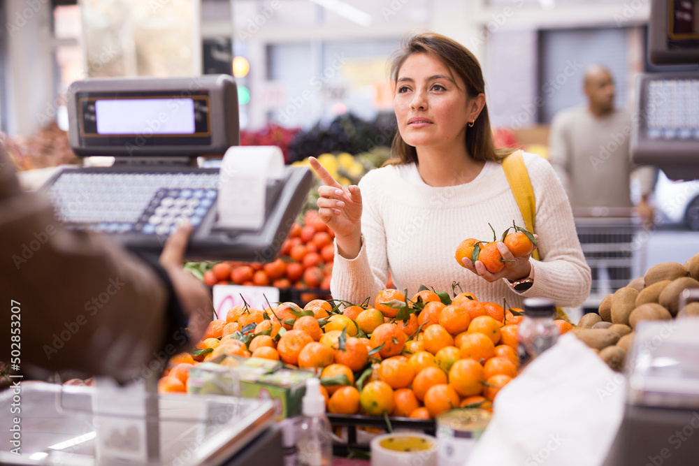 Customer selects ripe tangerines on the counter