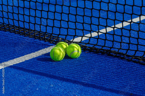 blue paddle tennis court, three balls near the net and the center line © Vic