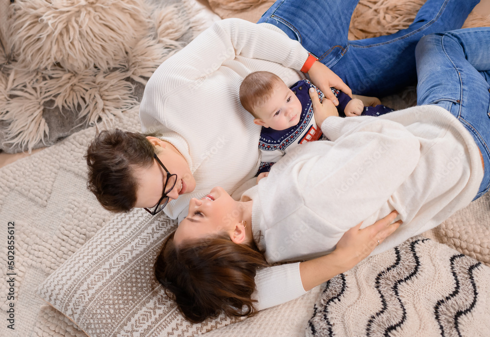 Young family dad moms and son lie on the carpet on the background of the New Year tree. High quality photo Young family dad moms and son lie on the carpet on the background of the New Year tree. High quality photo