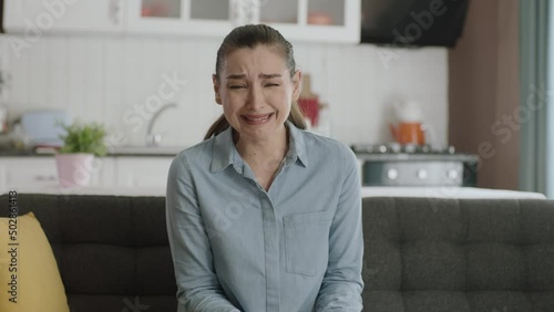 Sad worried young woman with psychological problem.Crying young woman sitting on sofa who lost a loved one. Portrait of sad young crying woman at home.