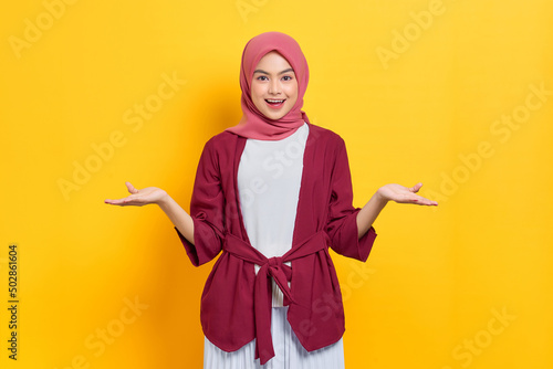 Overjoyed beautiful Asian woman in casual shirt celebrating big luck and success isolated over yellow background