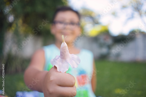 Thumbs up of unfocused boy with pink flower in hat © David